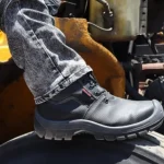 Bota de seguridad apoyada sobre maquinaria en una operación industrial